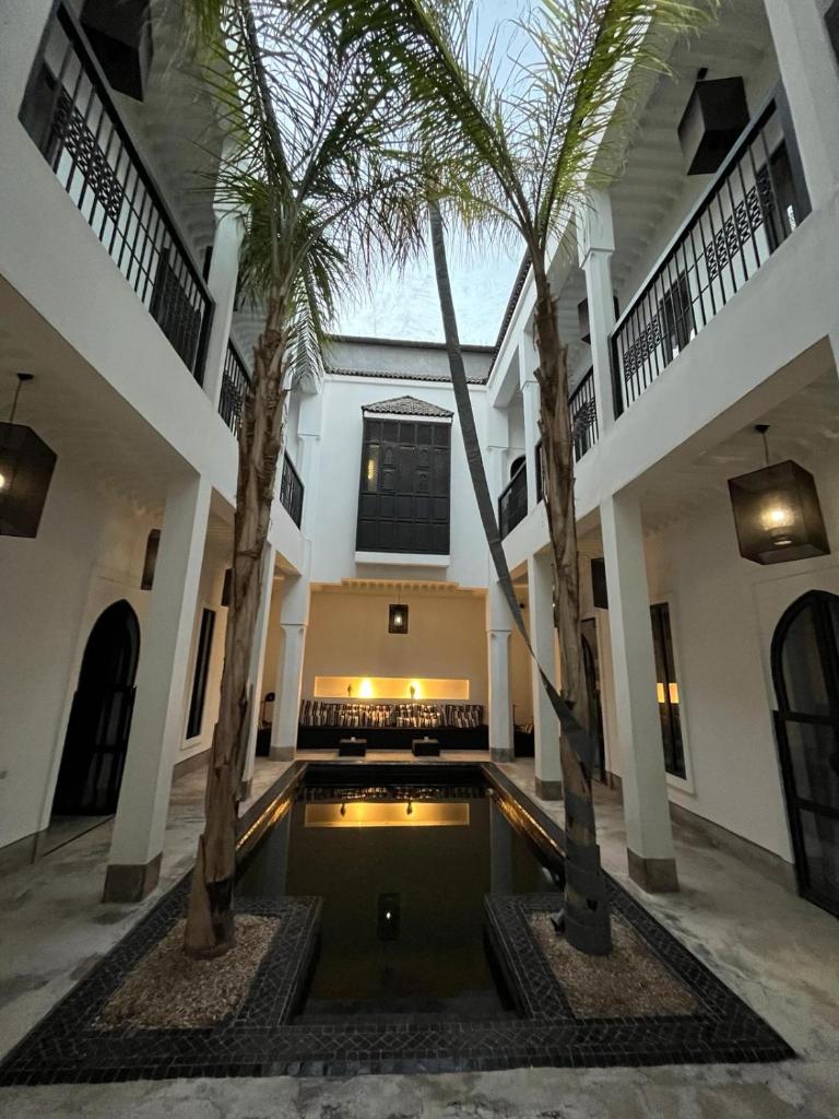 une cour avec des palmiers et une piscine dans l'établissement Riad First, à Marrakech