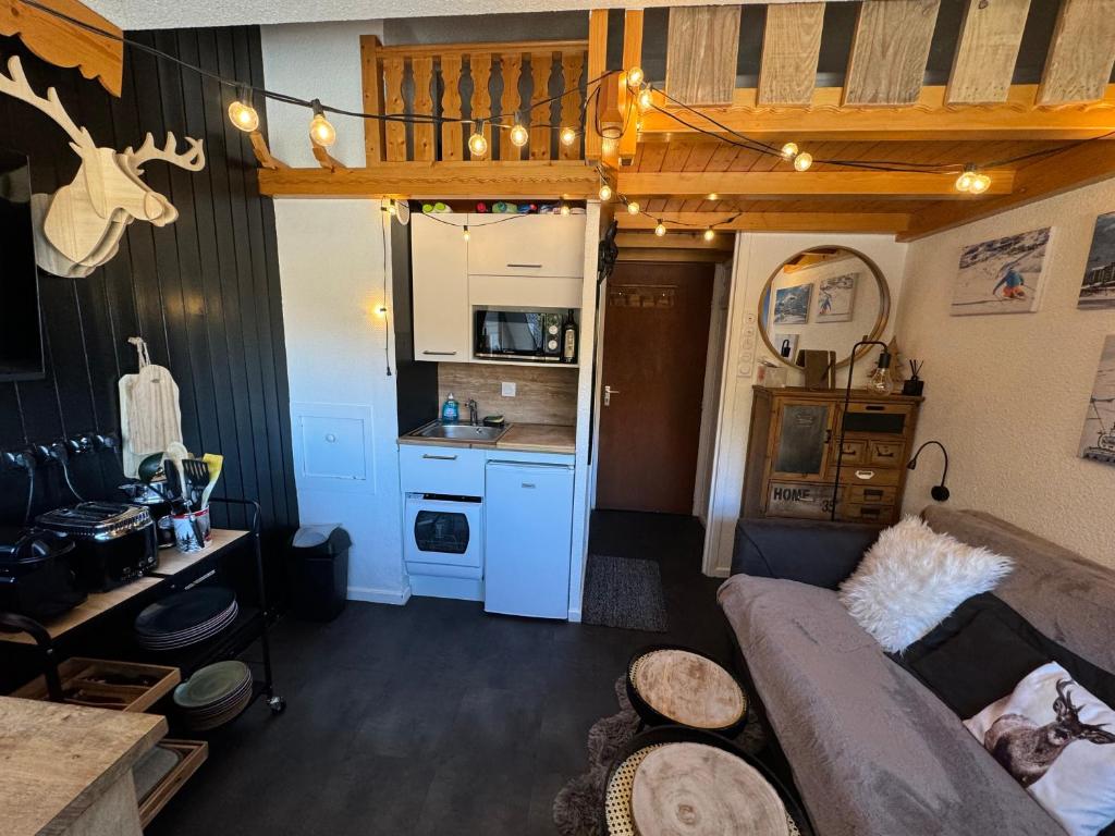 un salon avec un canapé et une cuisine dans l'établissement Les Menuires centre! Chaleureux studio sur les pistes!, aux Menuires