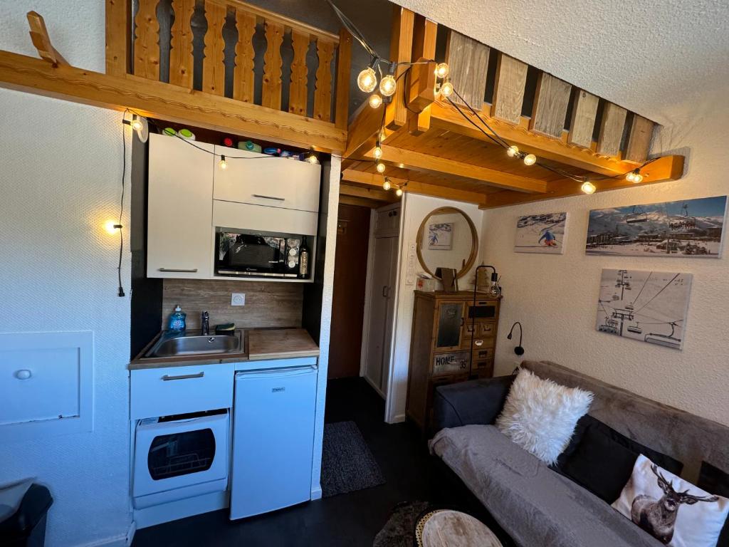 un petit salon avec un canapé et une cuisine dans l'établissement Les Menuires centre! Chaleureux studio sur les pistes!, aux Menuires