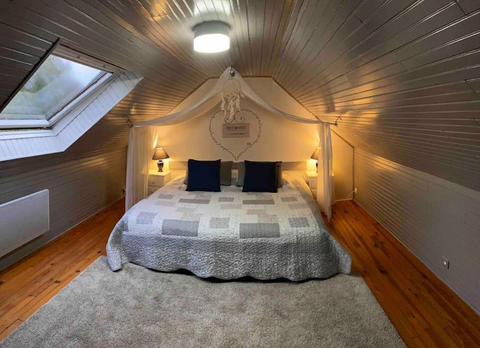 une chambre avec un grand lit dans un grenier dans l'établissement Gîte Cornouaille piscine ou jacuzzi, à Saint-Évarzec