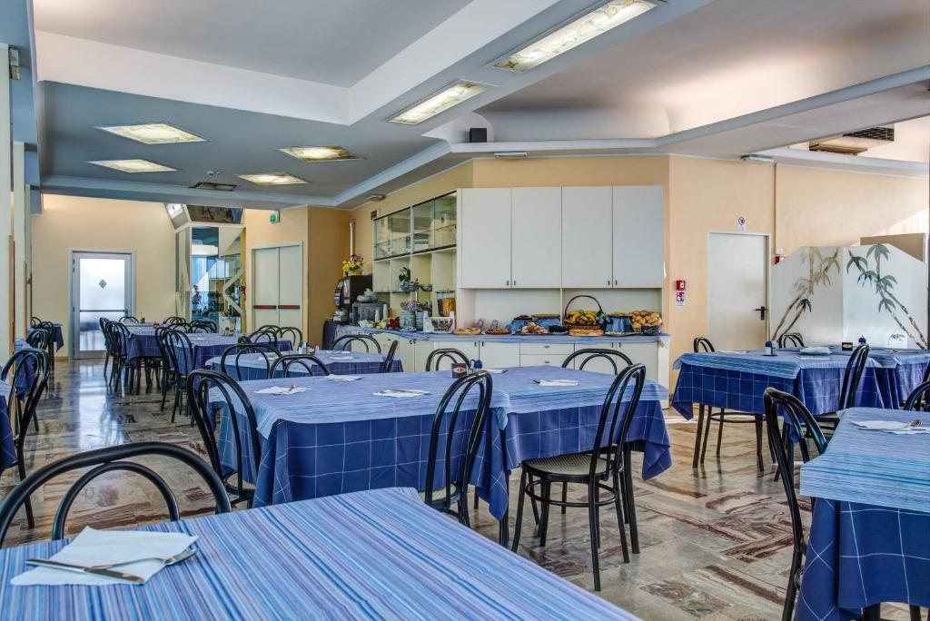 une cafétéria avec des tables et des chaises bleues et une cuisine dans l'établissement Hotel San Paolo, à Rimini