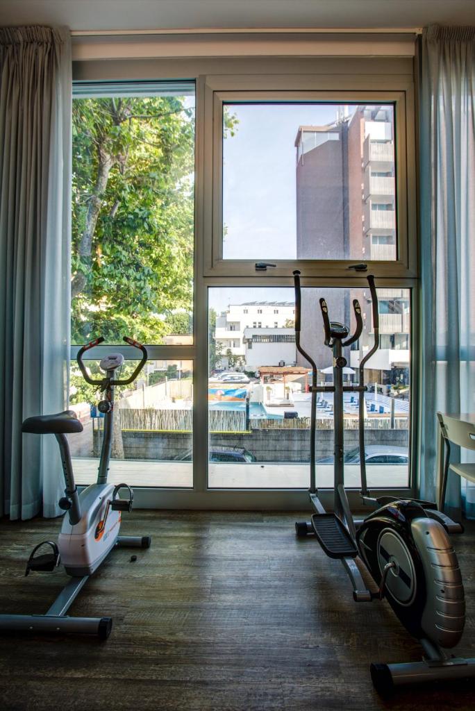 une salle de sport avec trois vélos d'exercice devant une fenêtre dans l'établissement Hotel San Paolo, à Rimini