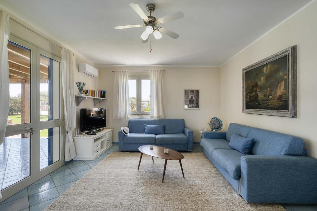 - un salon avec deux canapés bleus et une télévision dans l'établissement Villa Ficurinia, à Favignana