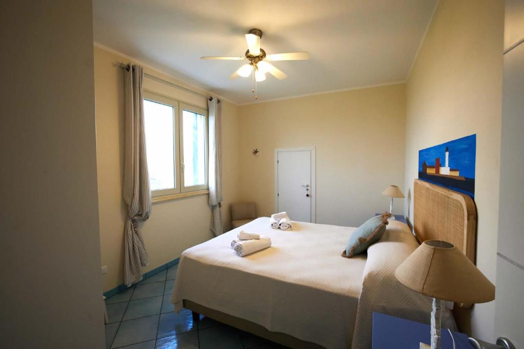 une chambre avec un lit avec un ventilateur de plafond dans l'établissement Villa Ficurinia, à Favignana