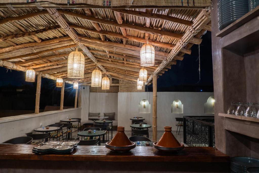 un restaurant avec des plafonds en bois, des tables et des lumières dans l'établissement Riad Nadalinn, à Marrakech