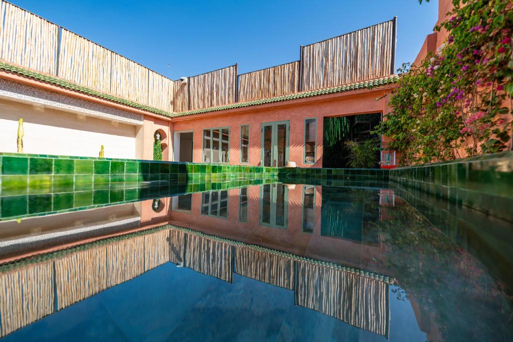 une piscine d'eau en face d'un bâtiment dans l'établissement Riad Cologne & Spa, à Marrakech