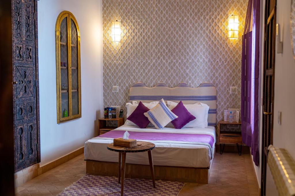 - une chambre avec un lit doté d'oreillers violets et d'une table dans l'établissement Riad Cologne & Spa, à Marrakech
