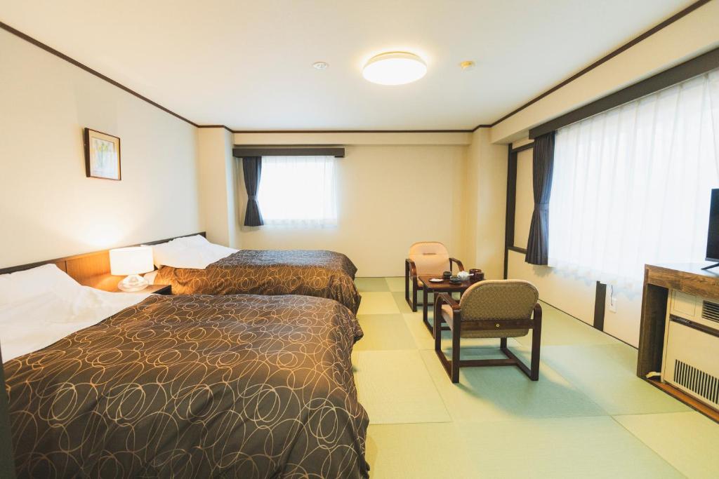 une chambre d'hôtel avec deux lits et une table dans l'établissement Onsen Yupopo, à Senboku