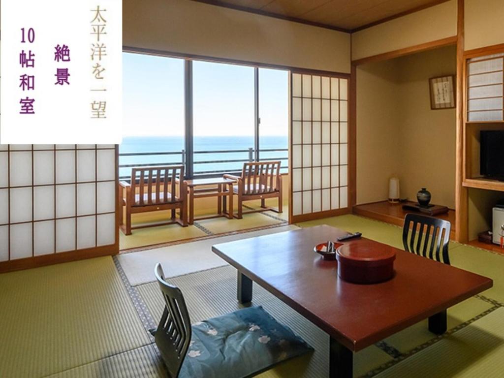 Cette chambre dispose d'une table et de chaises et offre une vue sur l'océan. dans l'établissement 絶景海風癒し庵 新八屋, à Toba