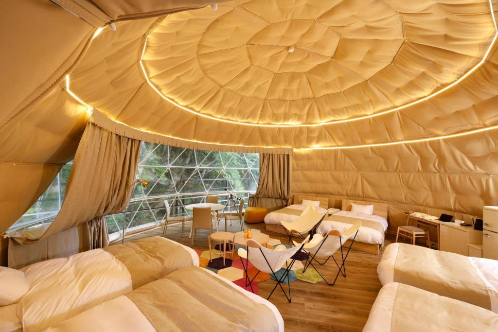 Cette chambre dispose de lits et d'un grand plafond. dans l'établissement 阿智星降りの宿やま星 Hotel&Glamp YAMABOSHI, à Achi