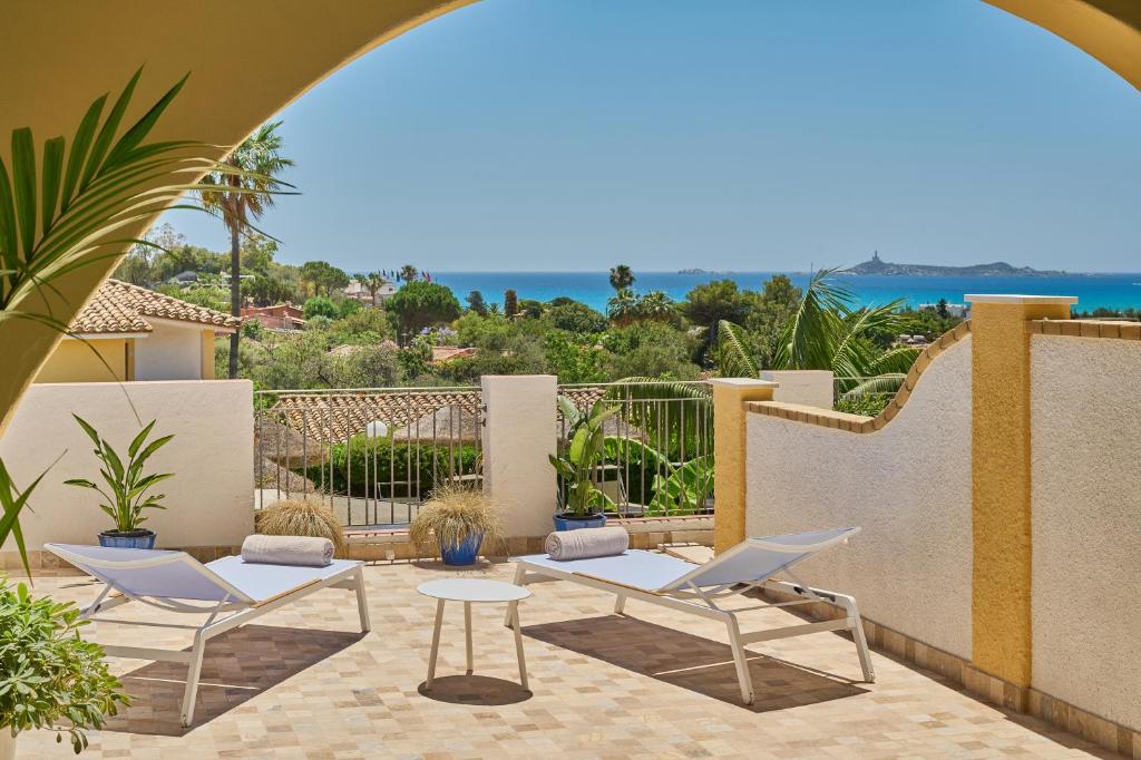 un patio avec deux chaises et une table et une vue sur l'océan dans l'établissement Residence Le Bouganville, à Villasimius