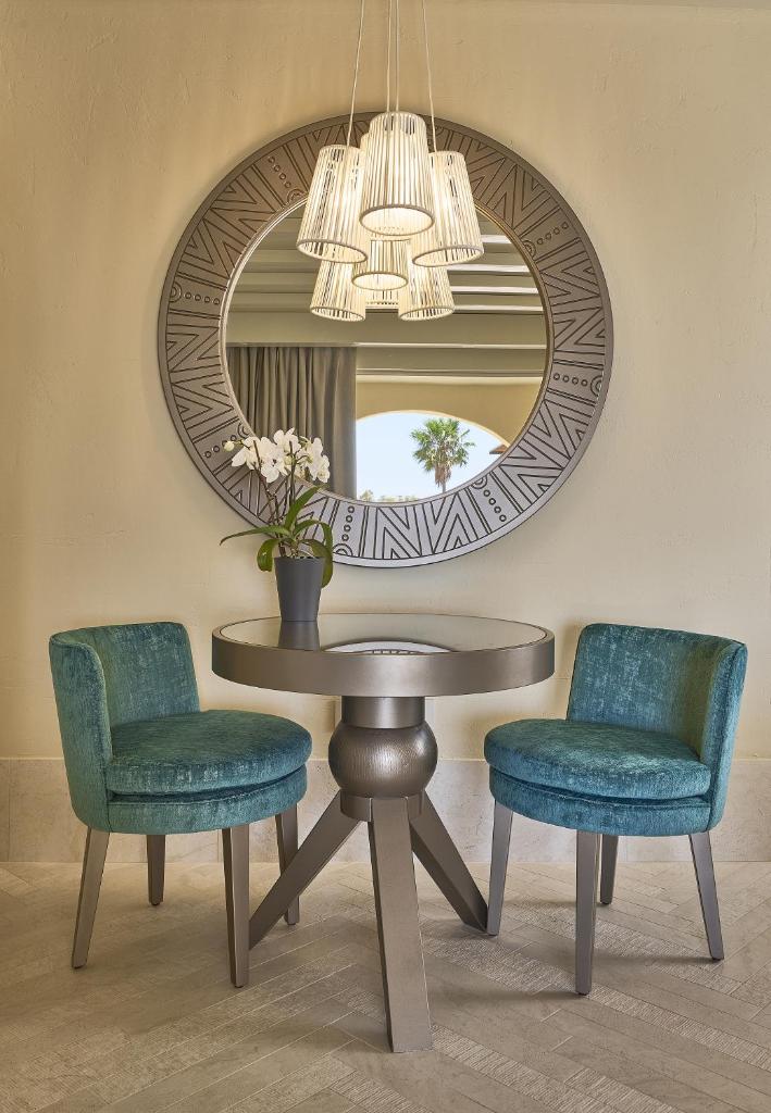 une table avec deux chaises et un miroir circulaire dans l'établissement Residence Le Bouganville, à Villasimius