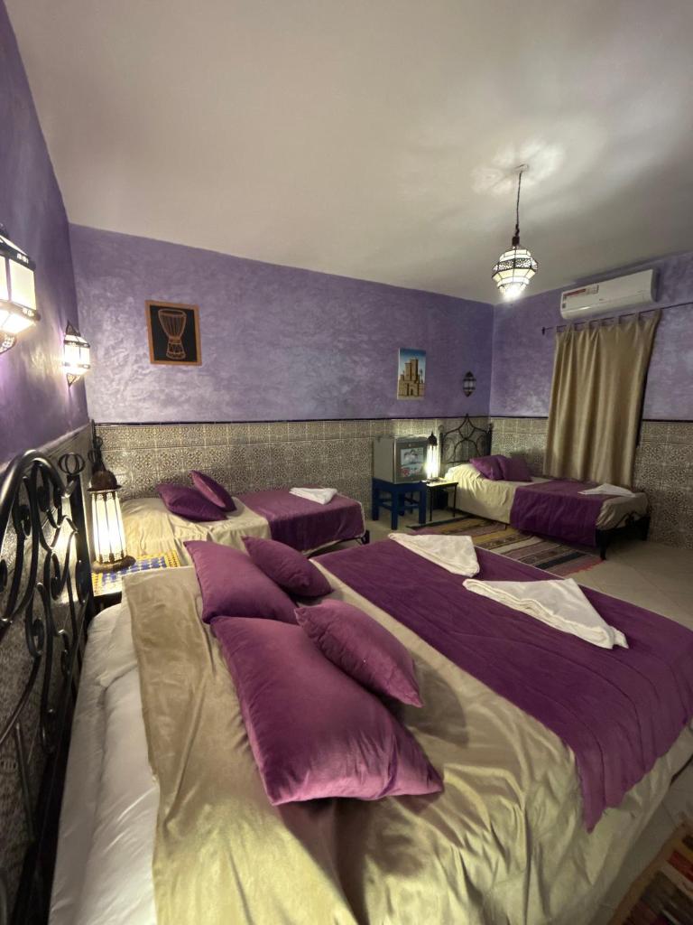 - une chambre avec 2 lits aux murs violets dans l'établissement Hotel Riad Ali, à Merzouga