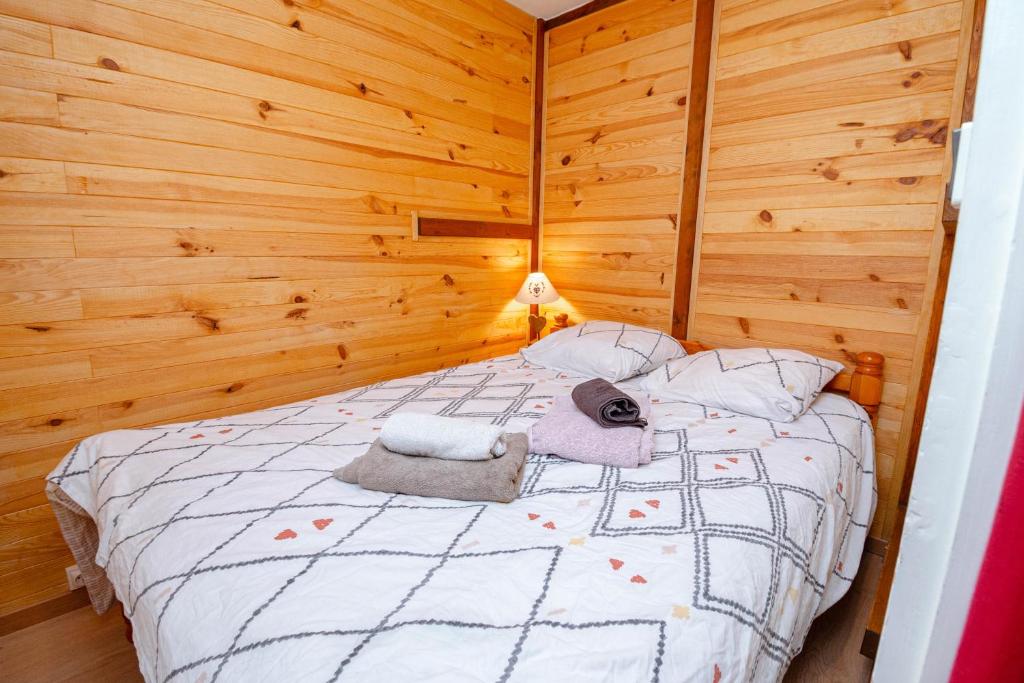 - une chambre avec un lit et des murs en bois dans l'établissement Au Doubs Refuge, à Métabief