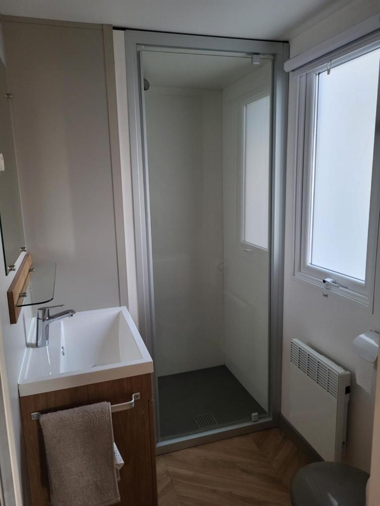 une salle de bain avec une douche, un lavabo et un miroir dans l'établissement Mobil Home spacieux Camping Mar Estang 4*, à Canet