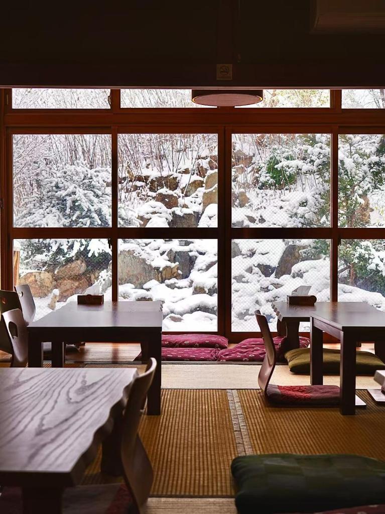 une pièce avec des tables et des chaises et une grande fenêtre dans l'établissement Plum House Otaru, à Otaru
