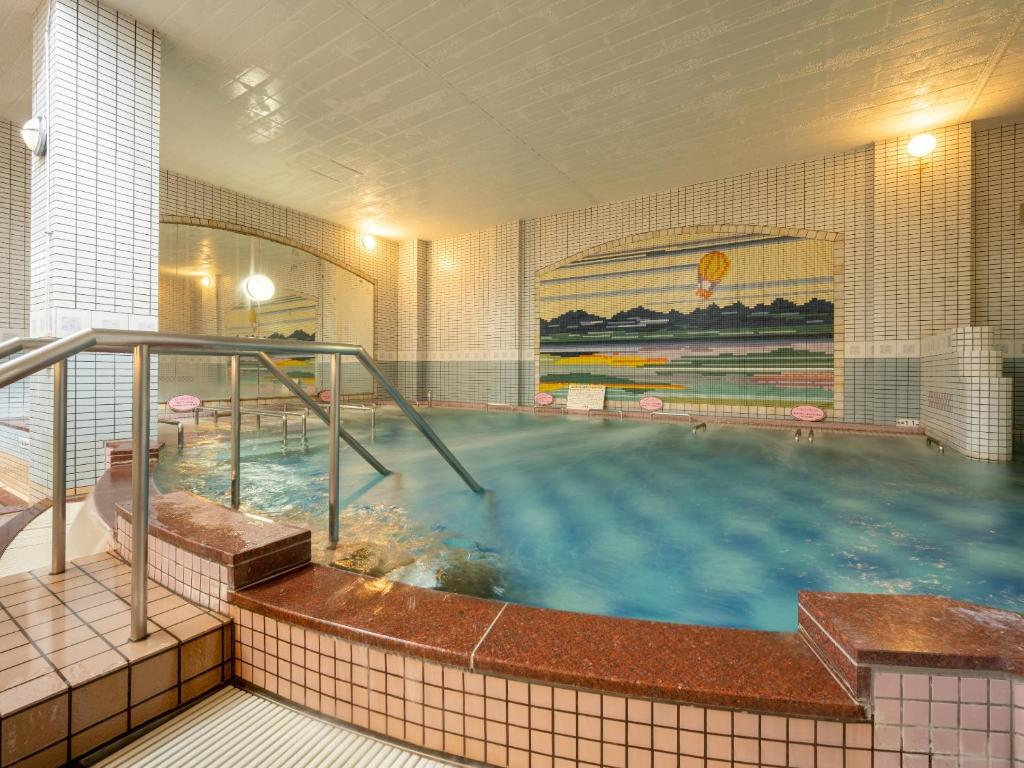une grande piscine d'eau dans un bâtiment dans l'établissement Hotel Daiheigen, à Otofuke 29 autres photos