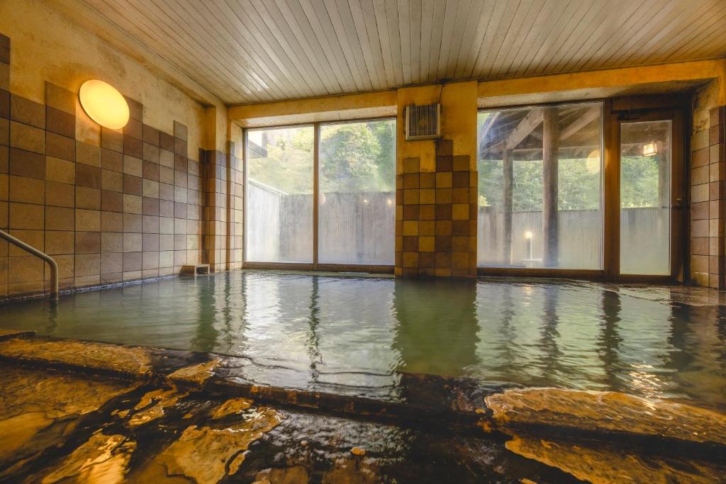 - une piscine d'eau vide dans une chambre avec fenêtres dans l'établissement Shikishimaso, à Higashikawa