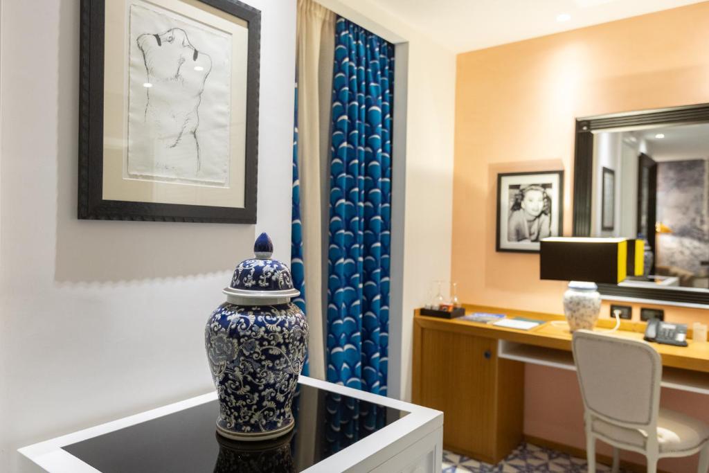 Cette chambre comprend un bureau et un vase sur une table. dans l'établissement Boutique Hotel Esplanade, à Paestum