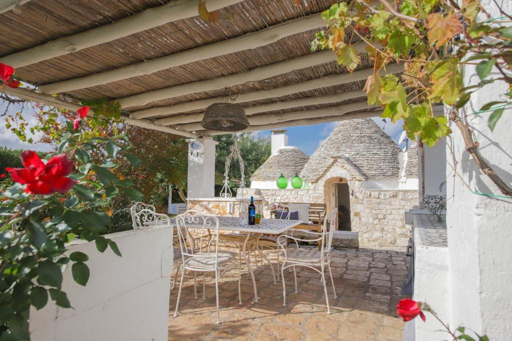 un patio avec une table et des chaises sous une pergola en bois dans l'établissement TD Trulli della Rosatella Typical Trulli with Pool, à Castellana Grotte
