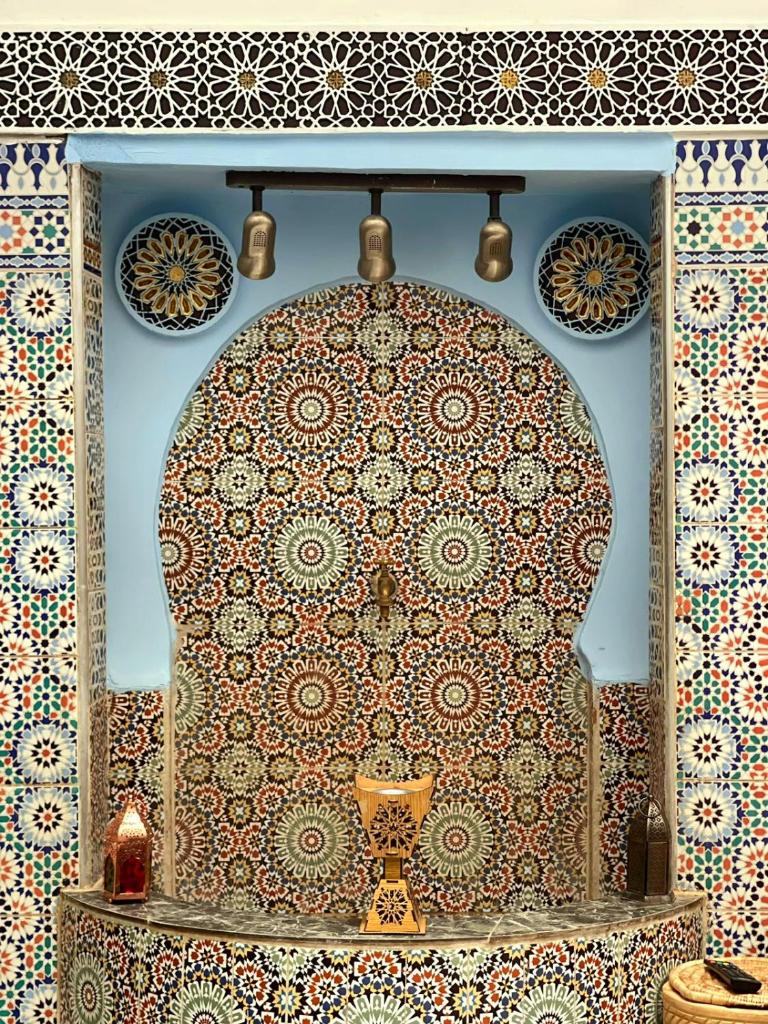 Cette chambre dispose d'une table avec un mur à motifs. dans l'établissement Dar Boujloud Fez, à Fès