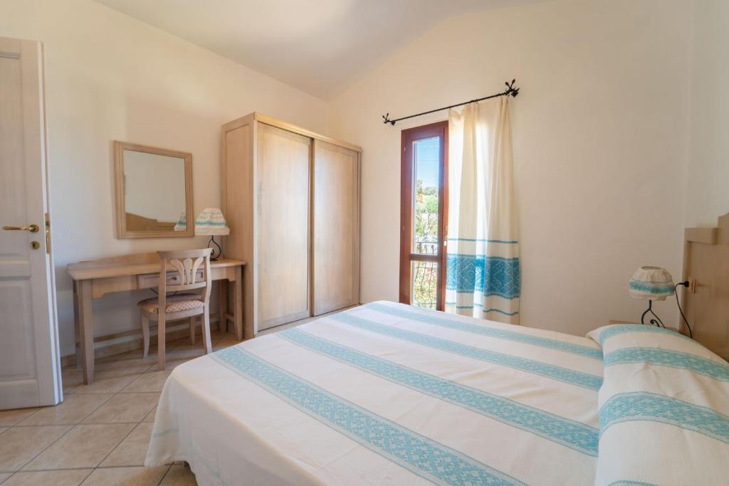 une chambre avec un lit, un bureau et une fenêtre dans l'établissement Residence Corte Dei Venti, à Budoni