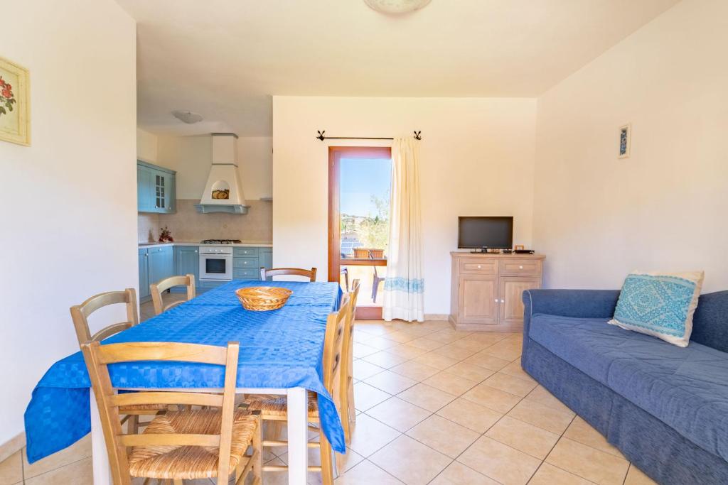une salle à manger avec une table bleue et un canapé dans l'établissement Residence Corte Dei Venti, à Budoni