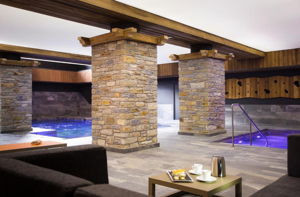 - un salon avec un mur en pierre et une piscine dans l'établissement Hôtel Saint Charles Val Cenis, à Lanslebourg-Mont-Cenis