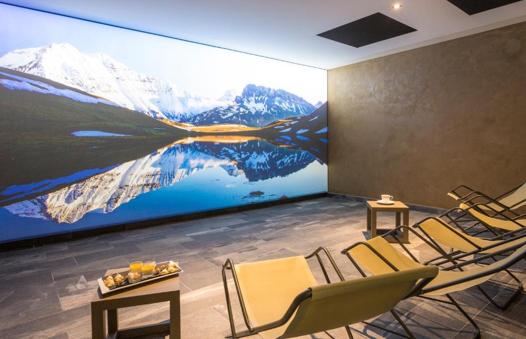 une chambre avec des chaises et un grand tableau sur le mur dans l'établissement Hôtel Saint Charles Val Cenis, à Lanslebourg-Mont-Cenis 37 autres photos