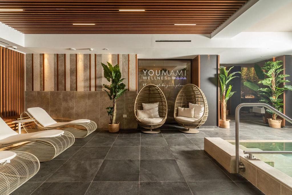 un hall avec des chaises en osier et une piscine dans l'établissement YOUMAMI Suite Hotel Wellness&Spa, à Giulianova