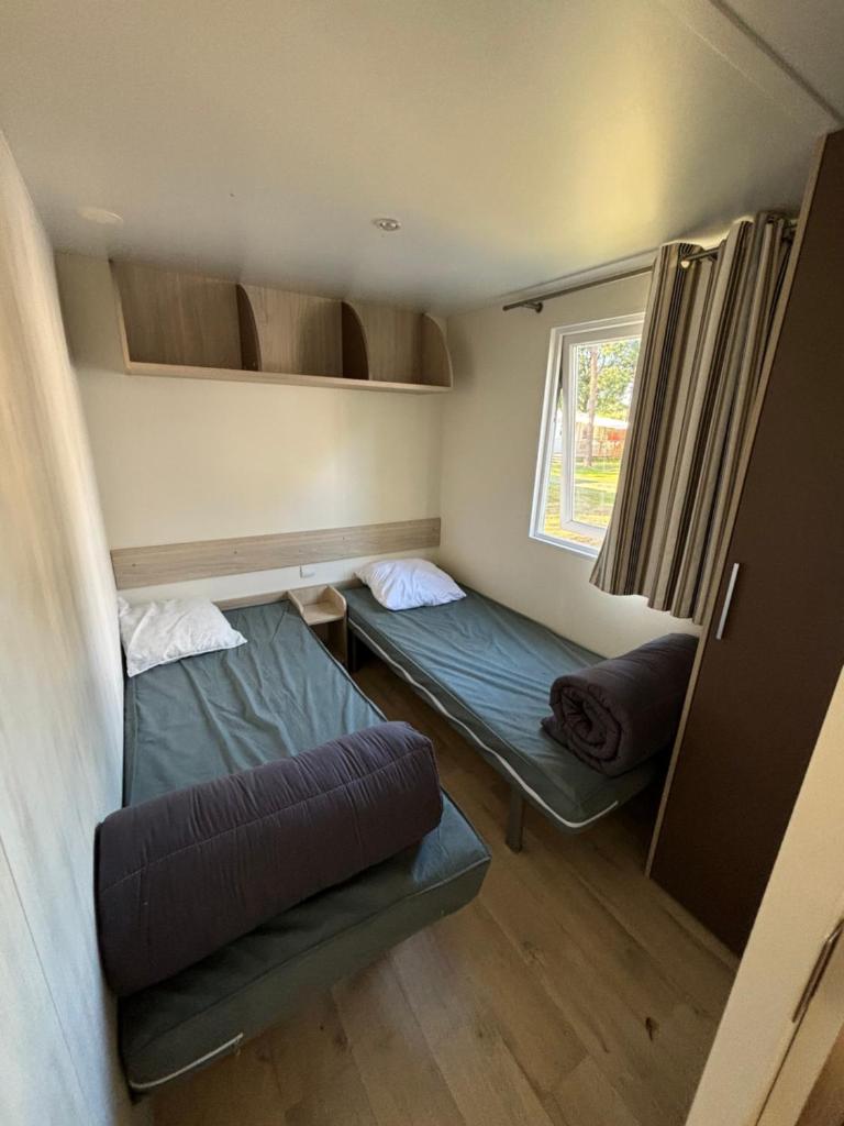 une petite chambre avec deux lits et une fenêtre dans l'établissement Louisiane 1, à Le Pont Legé