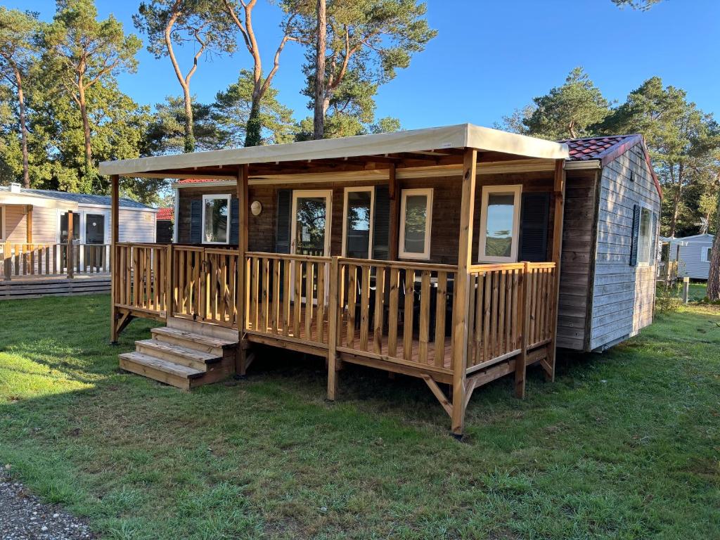 une cabane en bois avec une terrasse sur l'herbe dans l'établissement Louisiane 1, à Le Pont Legé