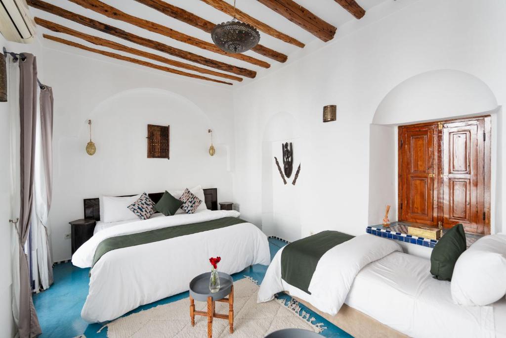 deux lits dans une chambre aux murs blancs dans l'établissement Riad Twilight, à Marrakech 37 autres photos