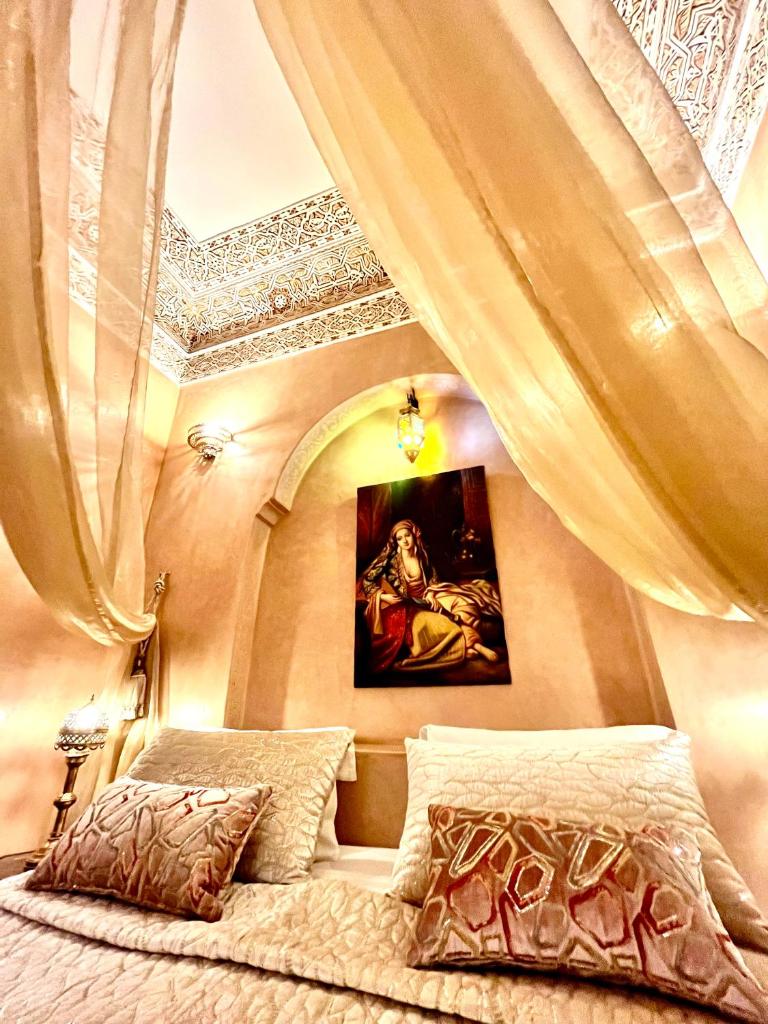 - une chambre avec un lit avec des rideaux et un tableau dans l'établissement Riad Fatinat Marrakech, à Marrakech