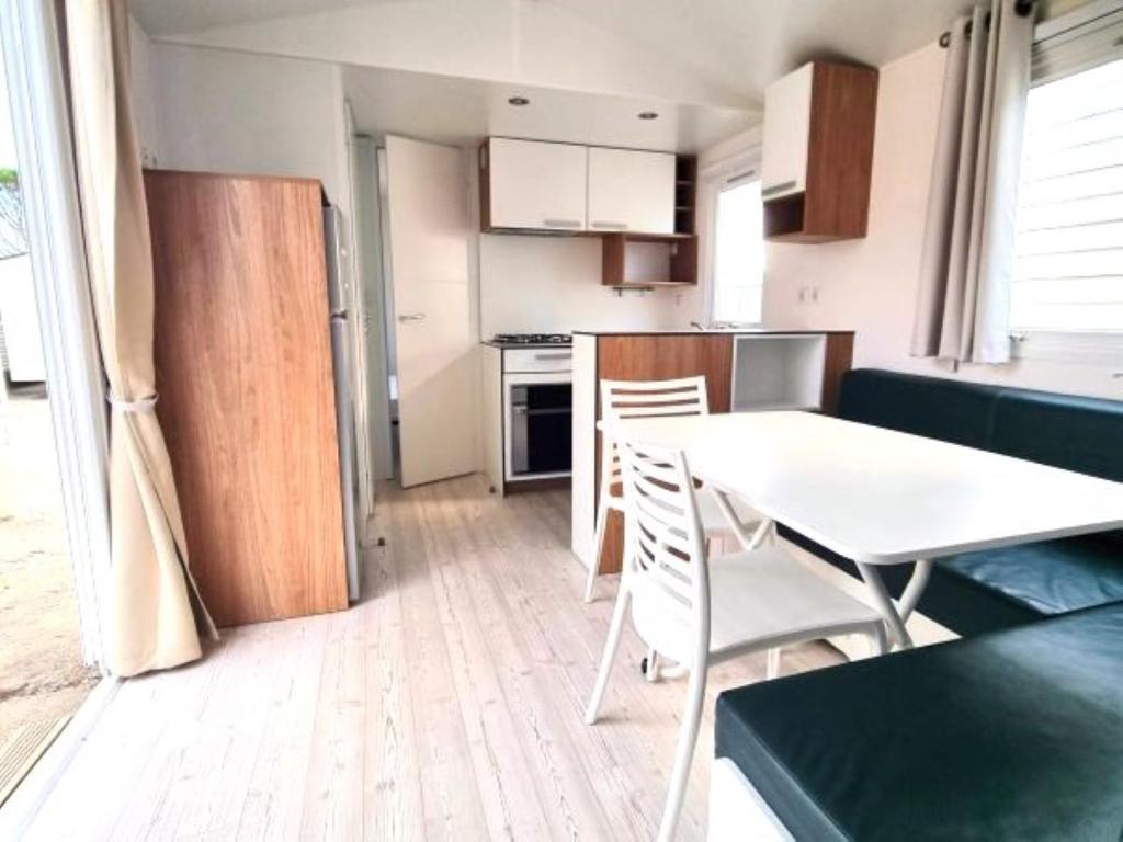 une petite cuisine avec une table et des chaises blanches dans l'établissement CAMPING VERT LAVANDE, à Belmont-sur-Rance