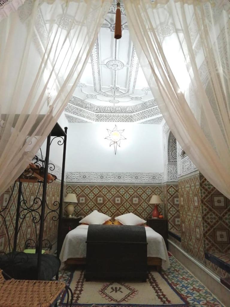 - une chambre avec un lit à baldaquin et un lustre dans l'établissement Dar Sarah-Mouassine-Marrakech, Riad authentique idéalement situé, à Marrakech