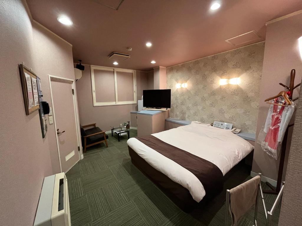 une chambre d'hôtel avec un lit et une télévision dans l'établissement ホテルロコズマウイ, à Honjo