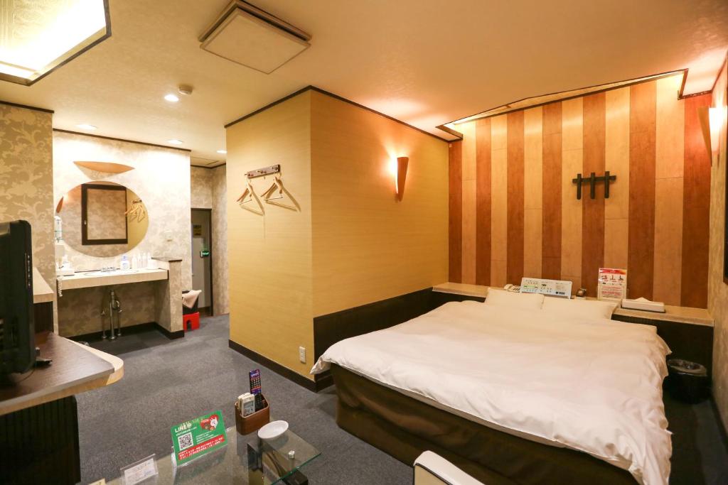 une chambre avec un grand lit avec une tête de lit en bois dans l'établissement ホテルロコズマウイ, à Honjo