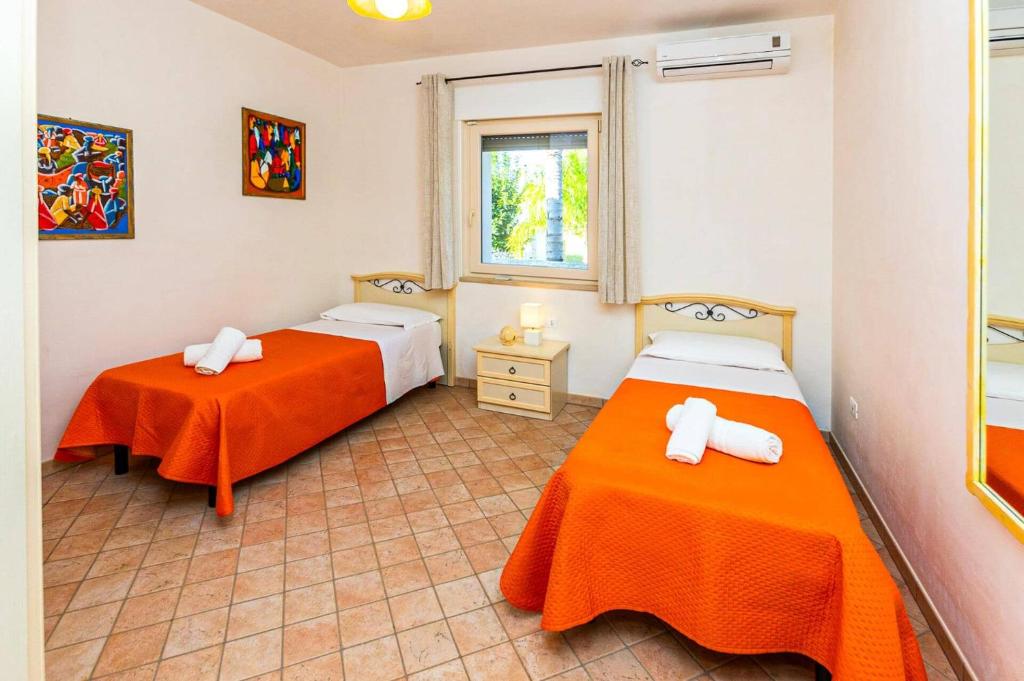 deux lits dans une chambre avec des draps orange dans l'établissement Villa Peppe by Villa Plus, à Carovigno