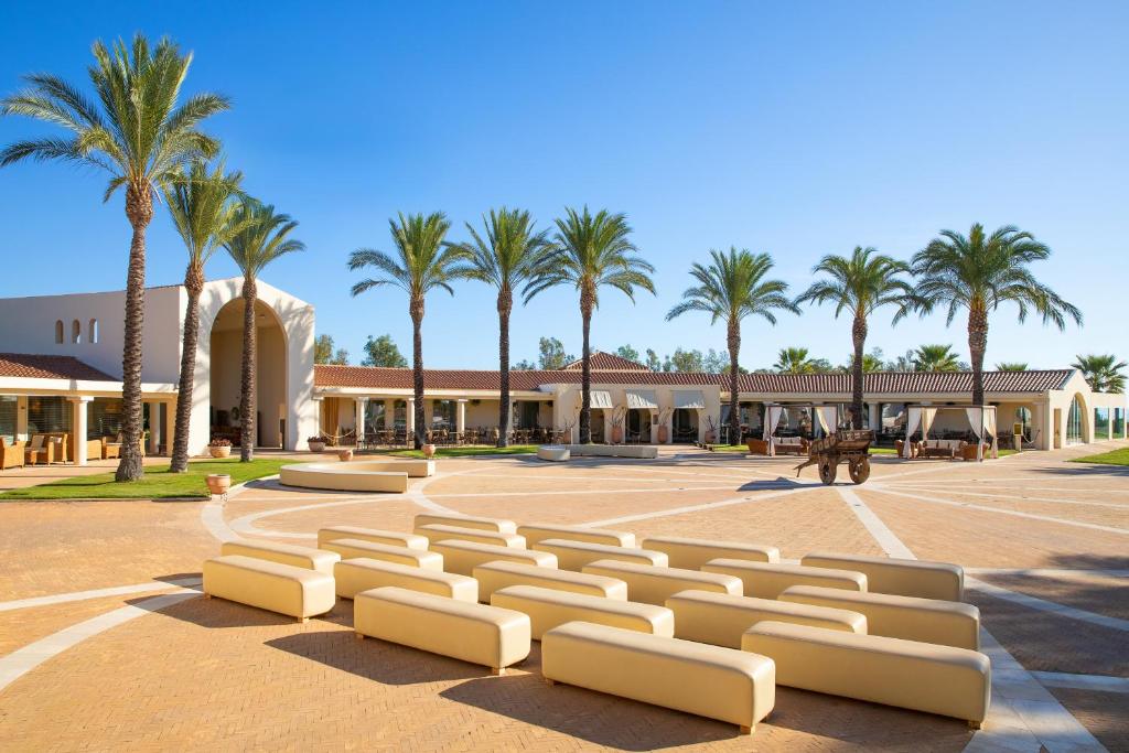 un grand parking avec des palmiers en arrière-plan dans l'établissement Spiagge San Pietro, a charming & relaxing resort, à Castiadas