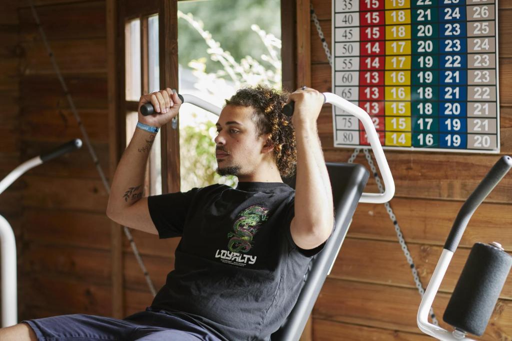un homme assis sur une balançoire dans une salle de sport dans l'établissement Camping de l'Etang du Pays Blanc, à Guérande