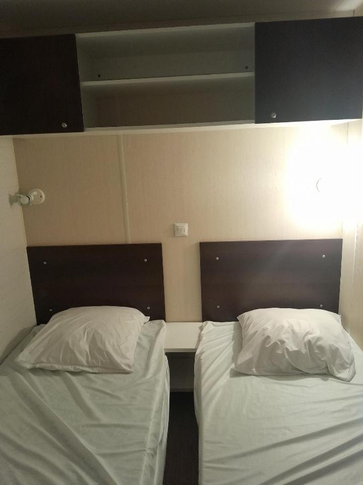 Cette chambre comprend 2 lits avec des draps et des oreillers blancs. dans l'établissement Camping Del Mar 137, Mobile Home O'Hara OTiny930, 3 chambres, 2 salles de bain, 6 personnes, bord de mer, à Argelès-sur-Mer