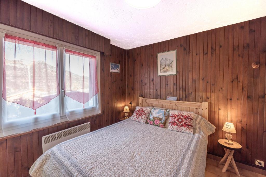 une chambre avec un lit avec des murs en bois et une fenêtre dans l'établissement Les Rocailles, à Notre-Dame-de-Bellecombe