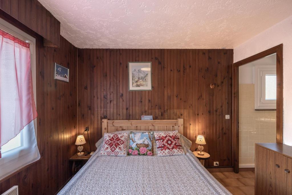 - une chambre avec des murs en bois et un lit avec deux lampes dans l'établissement Les Rocailles, à Notre-Dame-de-Bellecombe