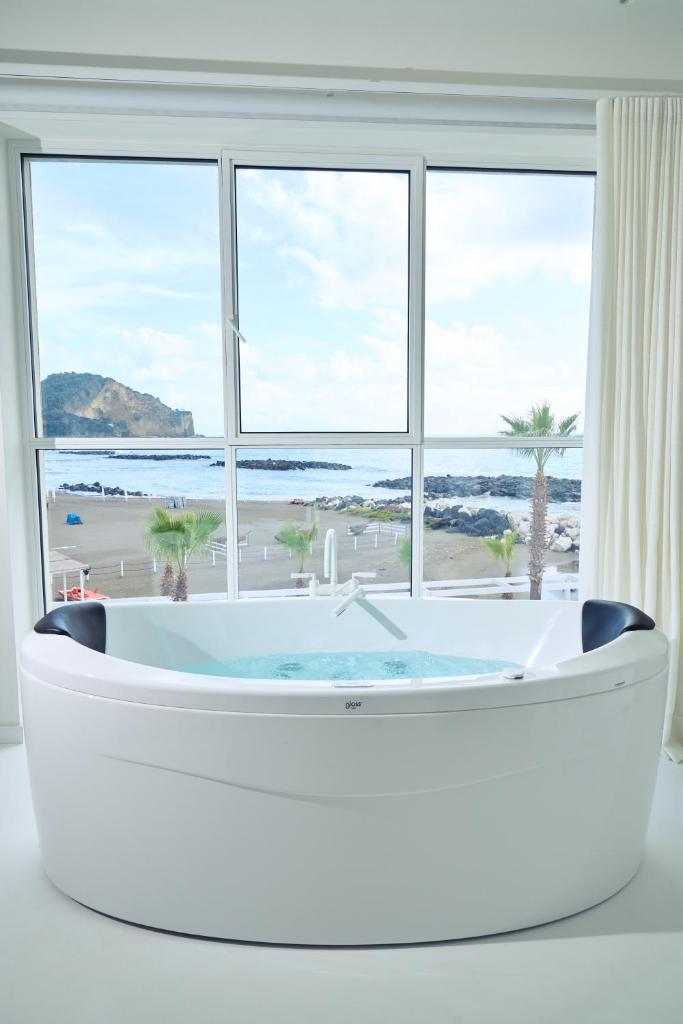 - une baignoire blanche dans une chambre dotée d'une grande fenêtre dans l'établissement CALEA Boutique Hotel, à Bacoli
