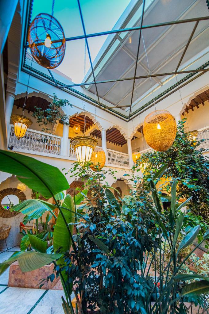 un hall d'entrée avec des plantes et des lustres dans un immeuble dans l'établissement Riad LAMDINA, à Marrakech