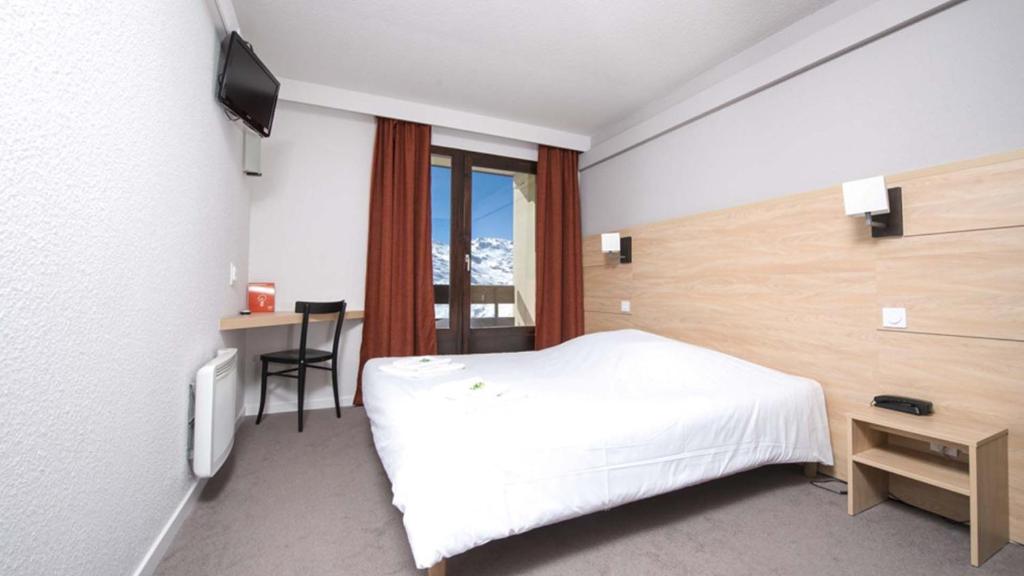 une chambre avec un lit, un bureau et une télévision dans l'établissement Villages Clubs du Soleil - LES MENUIRES, aux Menuires 29 autres photos