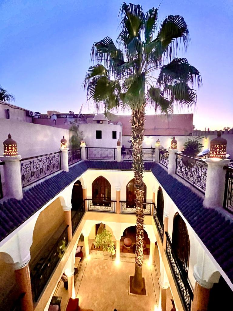 une cour intérieure avec un palmier dans un bâtiment dans l'établissement Riad Fatinat Marrakech, à Marrakech