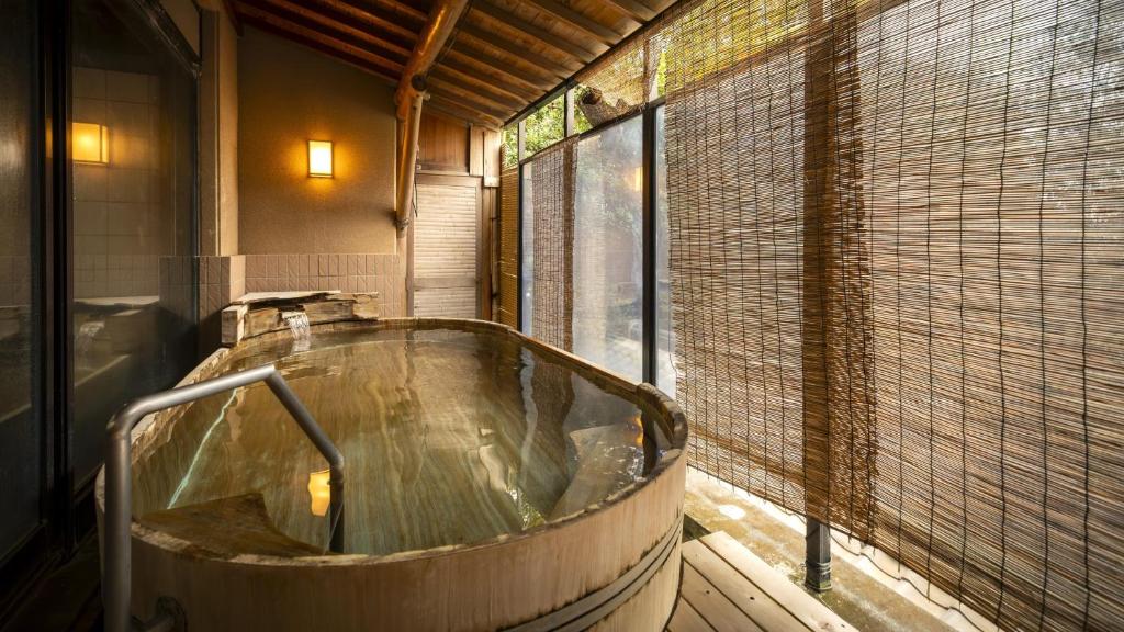 Cette chambre dispose d'une grande baignoire en bois et d'une fenêtre. dans l'établissement Nishiizu Koyoi, à Numazu