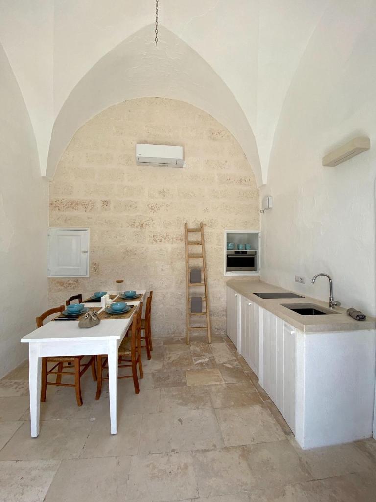 une cuisine avec une table, des chaises et un évier dans l'établissement Le Sette Valli, à Selva di Fasano
